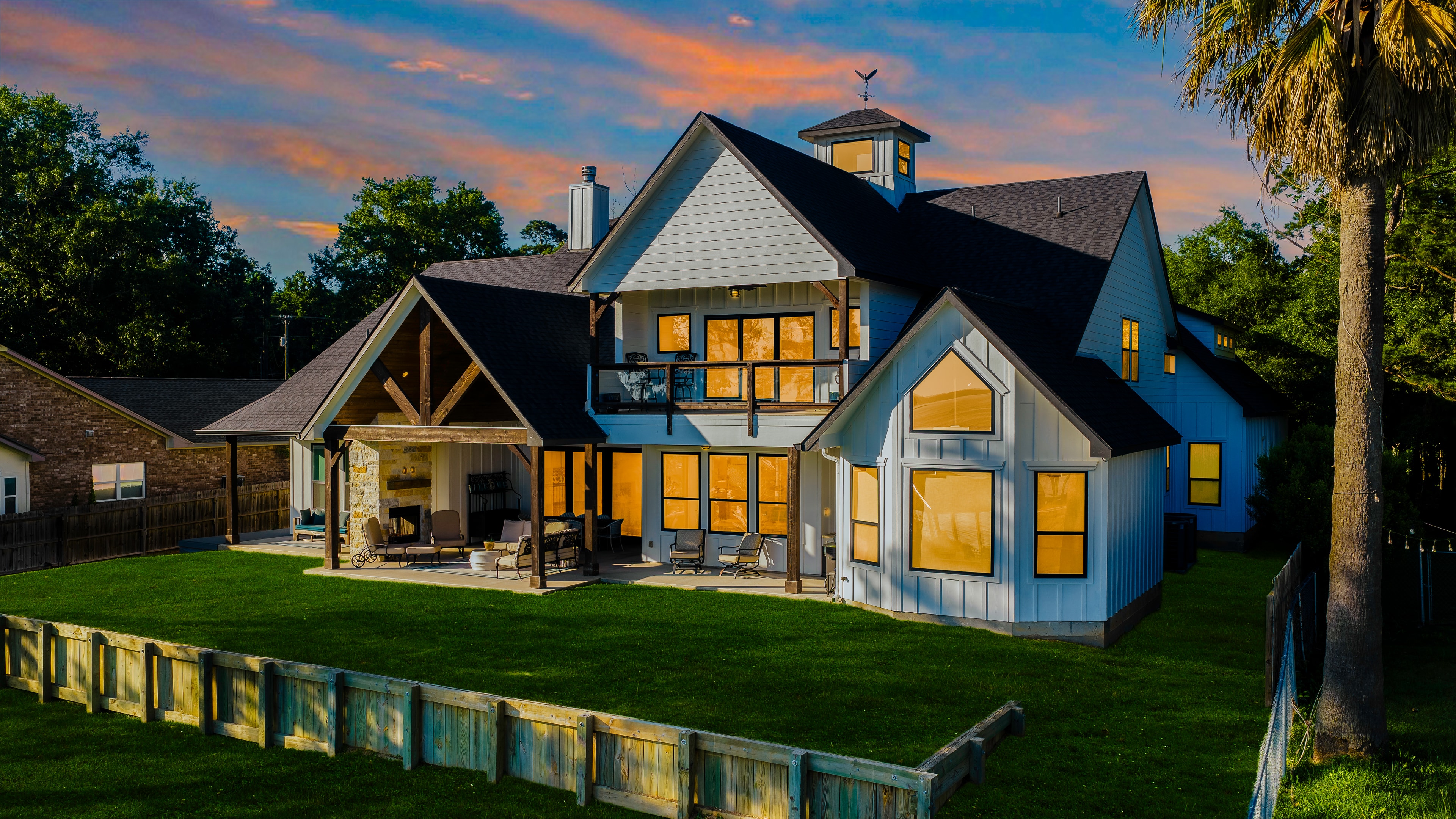 Lake house with illuminated windows at sunset